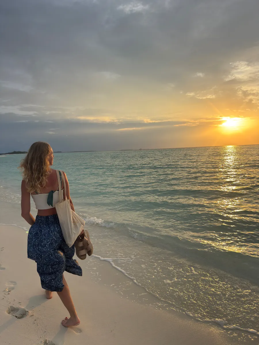 Viajera caminando por la playa al atardecer en Maldivas
